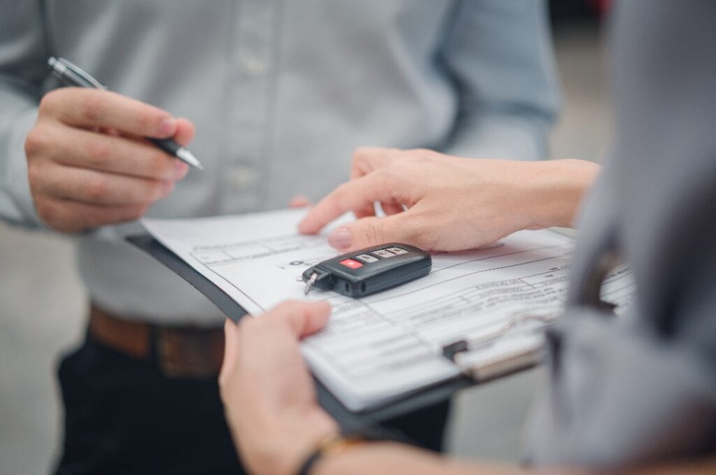 Autoverkauf oder Autovermietung Konzept, Closeup Dealership Manager Unterzeichnung Auto-Versicherung Dokument oder Leasing Papier Vertrag. Kunde mit Autohändler Vertreter machen Deal, unterschreiben auf Vereinbarung Dokument Vertrag im Büro