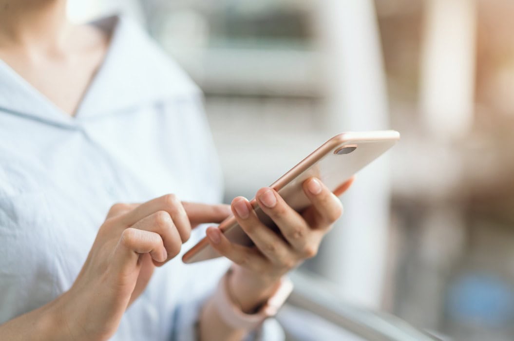 Frau, die ihr Smartphone auf einer Treppe in einem öffentlichen Bereich benutzt, in der Freizeit. Das Konzept der Nutzung des Telefons ist im täglichen Leben unerlässlich.