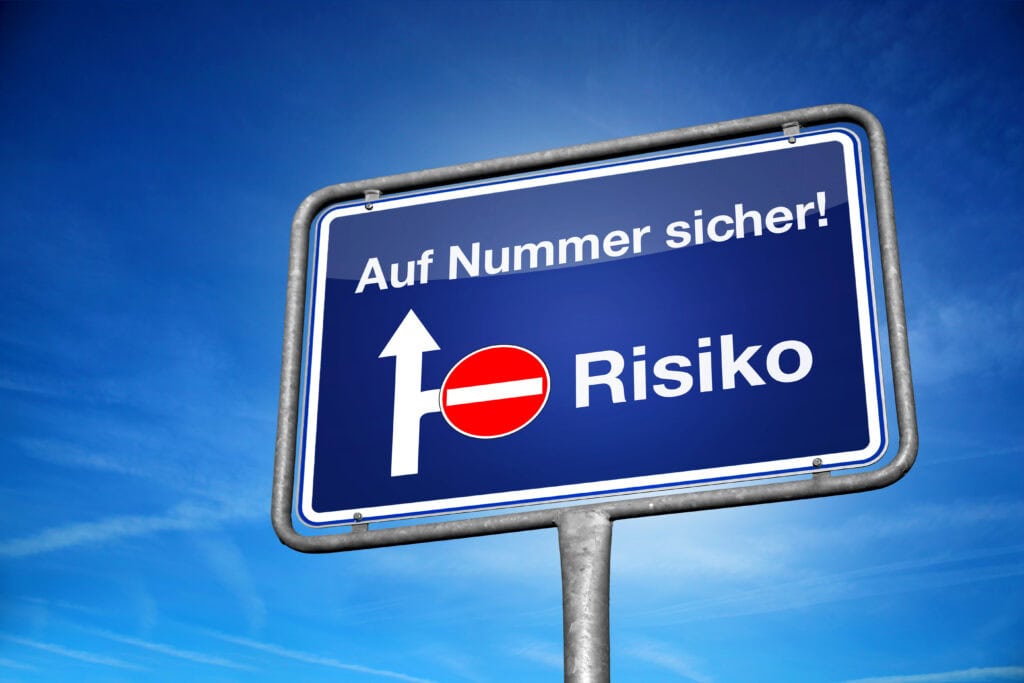 Ein blaues Straßenschild mit der Aufschrift "Auf Nummer sicher! Risiko" und einem Verbotsschild.