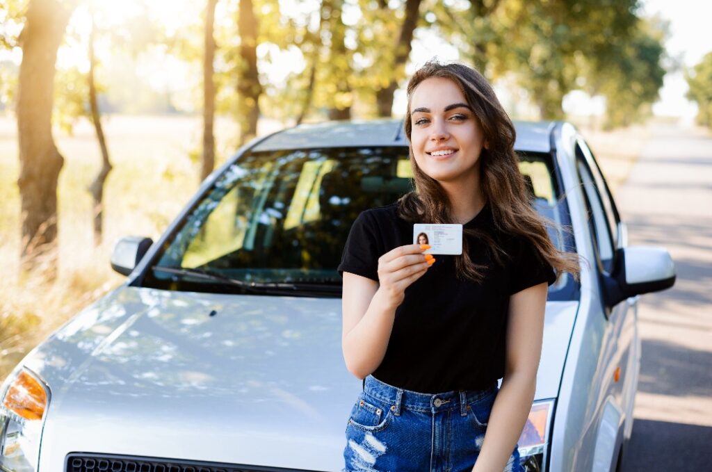 Der Teenager freut sich, den Führerschein zu erhalten. Konzept für den Kauf des ersten Autos